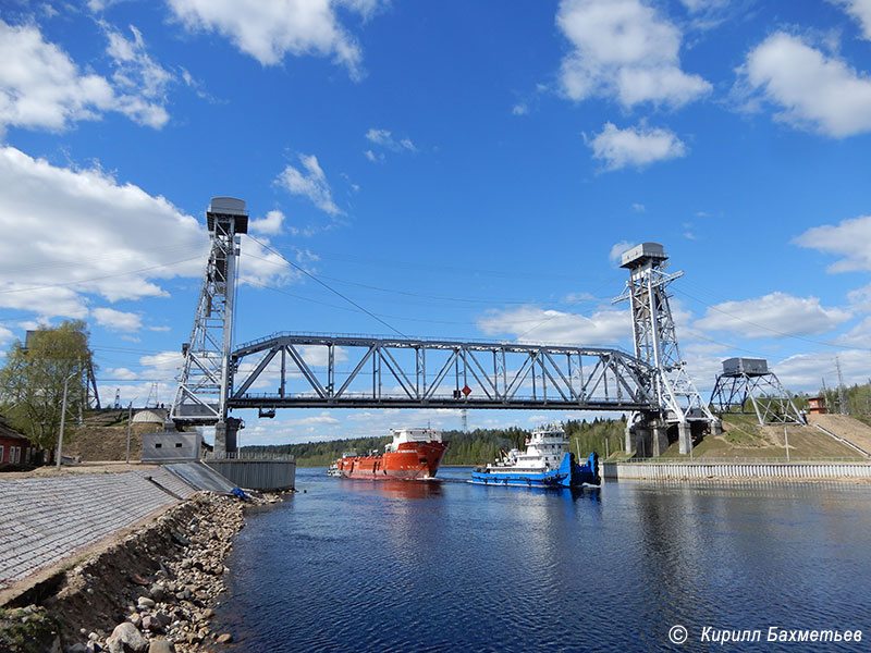Судно обеспечения нефтяных платформ "ФД Анбитбл" с буксирами "Барс" и "ОТА-990" под разведённым Подпорожским мостом через реку Свирь